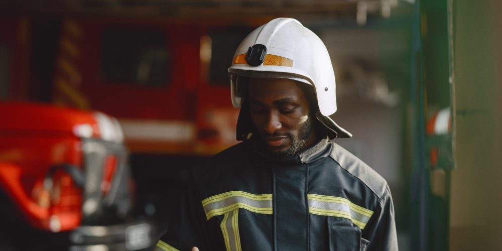 Arfican fireman in a uniform. Man prepare to work. Guy use radio transmitter.